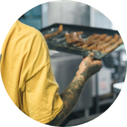 Chef holding a tray of cooked bacon